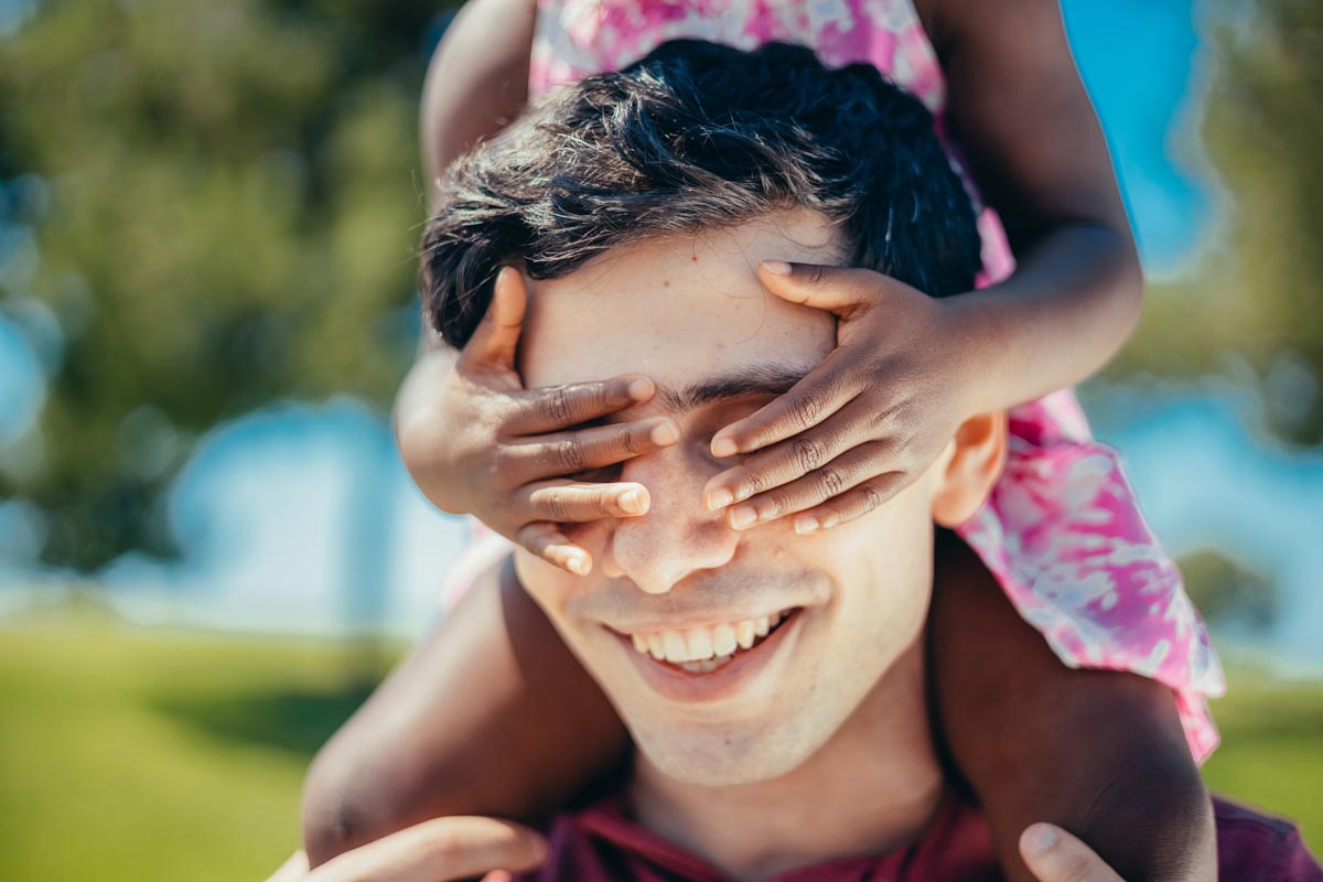 little girl covers mans eyes